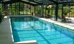 Piscine carrelée de 15 x 6 m avec escalier roman. Le toit vitré laisse passer toute la lumère dans l'espace piscine ce qui rend cette pièce très chaleureuse et agréable