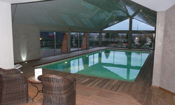 Piscine intérieur de 10 x 5 m avec Liner mosaïqué vert et plage périphérique en bois exotique
