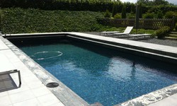 Piscine en maçonnerie de 10 m x 5 m avec margelle en béton à 2 niveau et un fond de couleur grise anthracite.