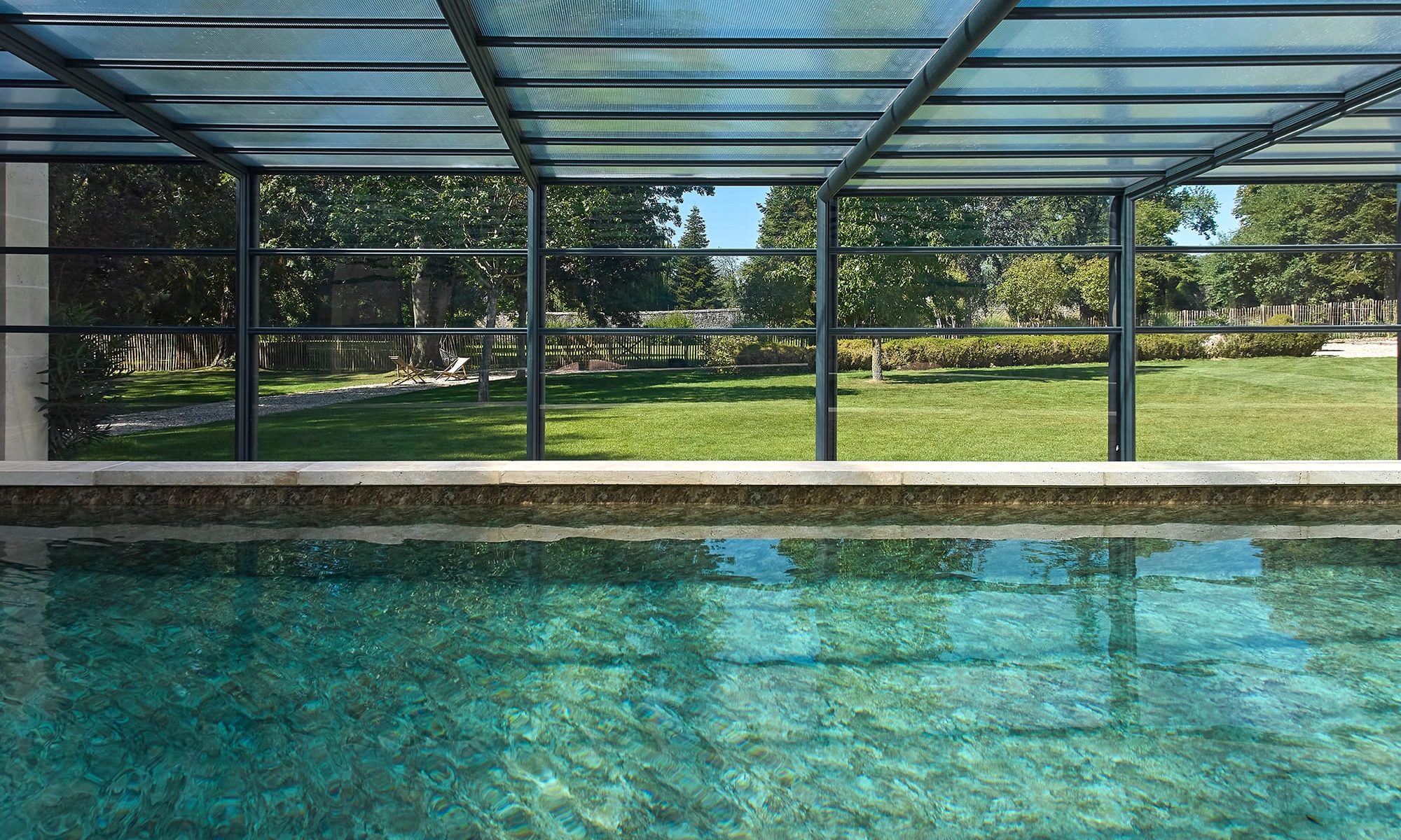 Piscine extérieure équipée d’un abri haut coulissant pour une utilisation prolongée.