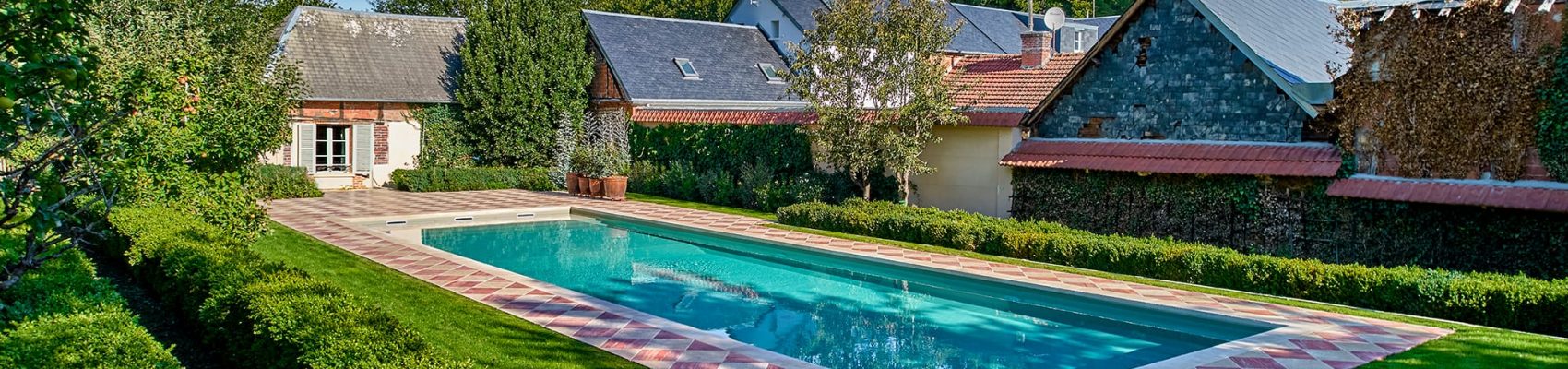 Couloir de nage entourée d’une terrasse en travertin rose et nuancé.