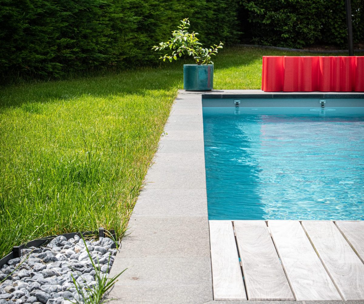 Piscine en L avec fond incurvé et margelles en pierre de Basalt