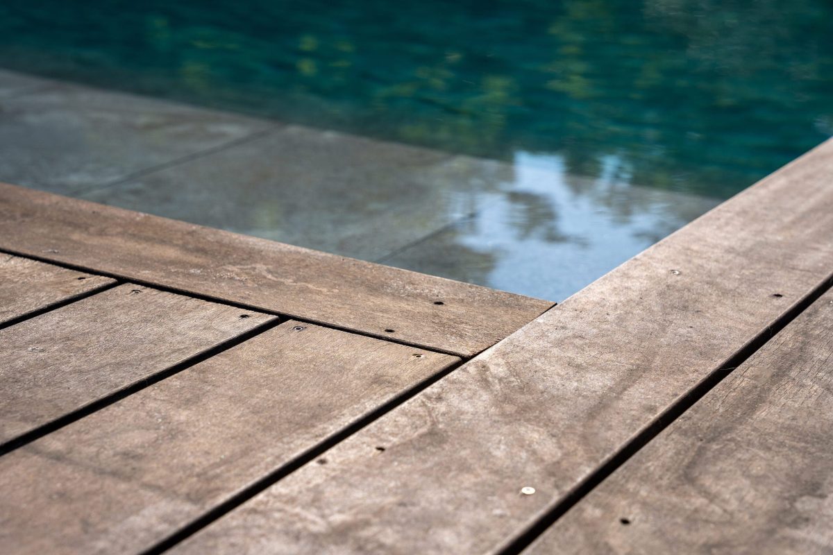 Piscine extérieure avec un volet In'Deck immergé et plages en bois - Réalisation Delalande Piscines & Spas
