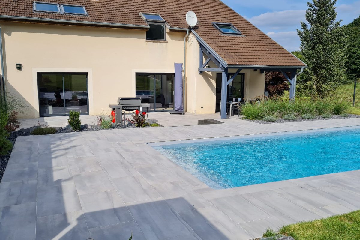 Aménagement d'un jardin avec terrasse en pierres naturelles et piscine rectangulaire - Delalande Piscines & Spas